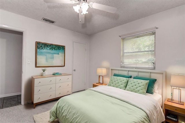 bedroom featuring ceiling fan, a textured ceiling, and light carpet