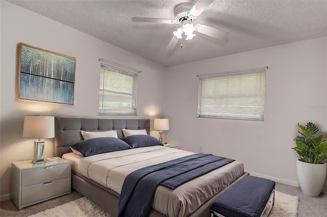 bedroom featuring ceiling fan, light colored carpet, and a textured ceiling