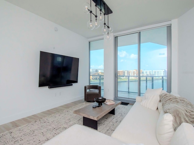 living room with an inviting chandelier, a wall of windows, and hardwood / wood-style floors