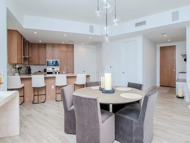 dining space with sink and light hardwood / wood-style flooring