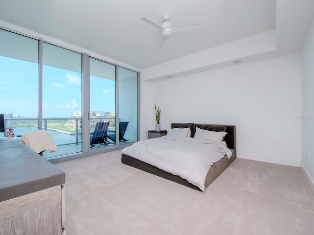 bedroom with ceiling fan, light carpet, access to exterior, expansive windows, and a water view