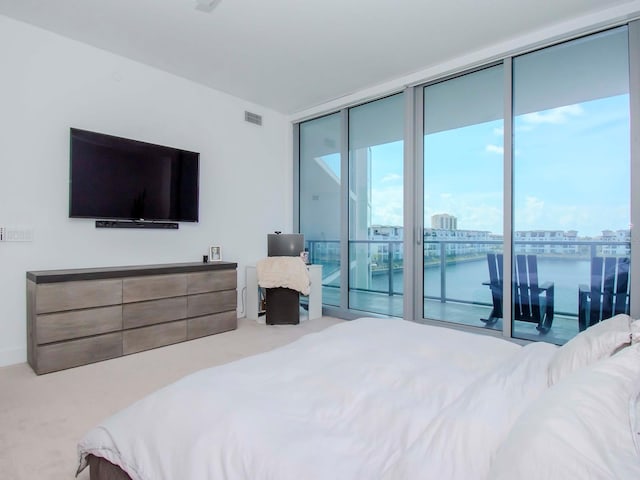 bedroom featuring carpet flooring, a water view, expansive windows, and access to outside