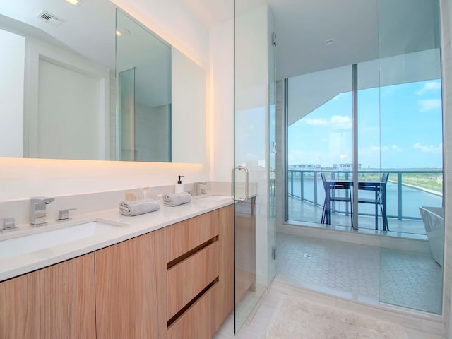 bathroom featuring tile patterned flooring, a shower with door, a water view, and vanity