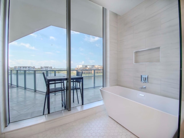 bathroom featuring a bathtub, tile walls, tile patterned floors, and a water view