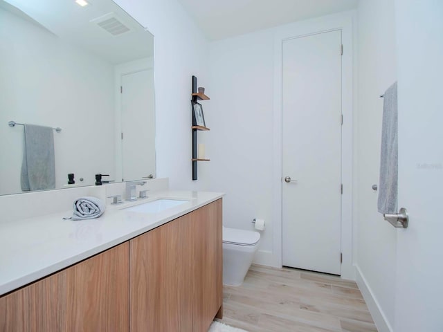 bathroom with hardwood / wood-style flooring, vanity, and toilet