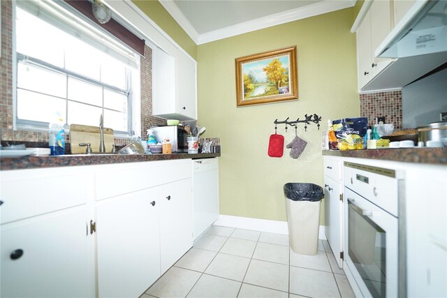 kitchen with white cabinets, backsplash, light tile patterned floors, white appliances, and ornamental molding