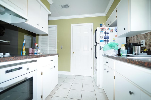 kitchen with light tile patterned floors, crown molding, white oven, white cabinetry, and tasteful backsplash