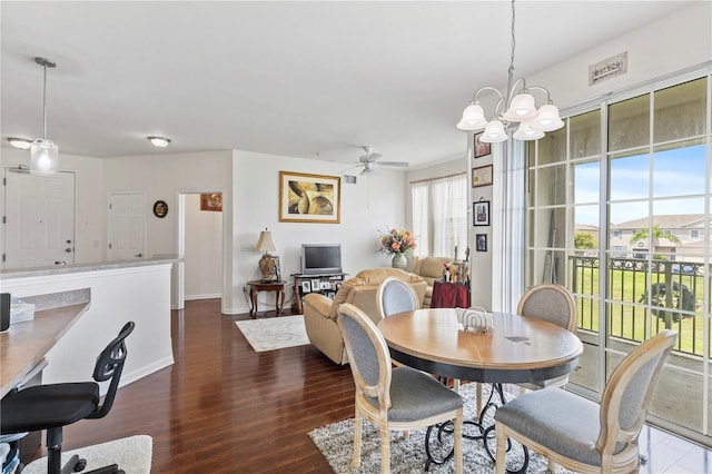 dining room with ceiling fan with notable chandelier and dark hardwood / wood-style floors