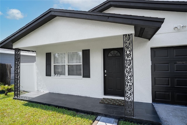 property entrance featuring an attached garage and stucco siding