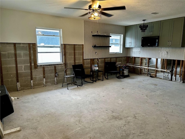 interior space with visible vents, ceiling fan, unfinished concrete floors, a textured ceiling, and green cabinets