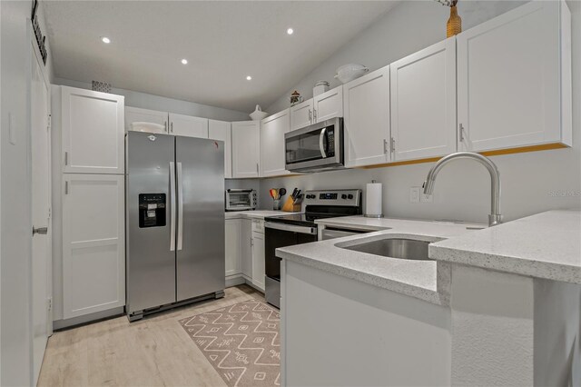 kitchen with sink, light stone counters, appliances with stainless steel finishes, light hardwood / wood-style floors, and white cabinets