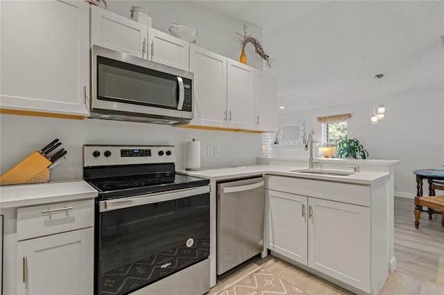 kitchen with white cabinetry, sink, stainless steel appliances, and kitchen peninsula