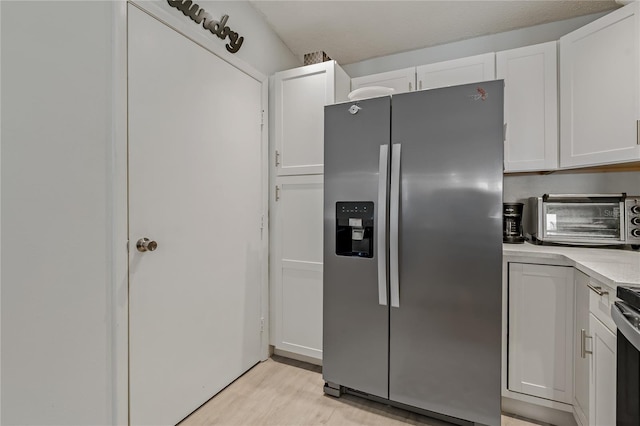 kitchen featuring stainless steel fridge with ice dispenser, light hardwood / wood-style flooring, and white cabinets