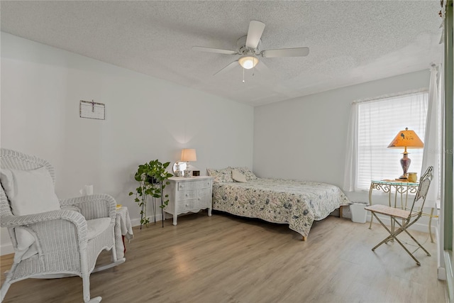 bedroom with ceiling fan, wood-type flooring, and a textured ceiling