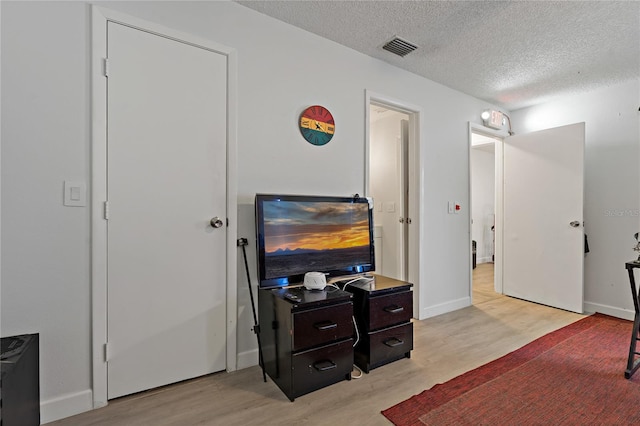 bedroom featuring light hardwood / wood-style floors and a textured ceiling