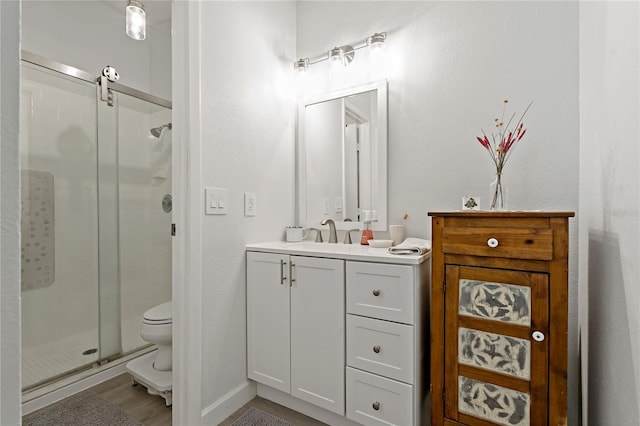 bathroom with vanity, hardwood / wood-style flooring, a shower with shower door, and toilet