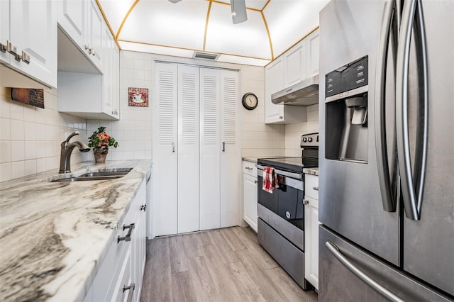 kitchen with appliances with stainless steel finishes, light hardwood / wood-style floors, tasteful backsplash, sink, and white cabinets