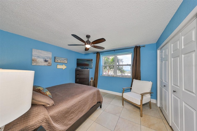 bedroom with light tile patterned floors, a textured ceiling, a closet, and ceiling fan