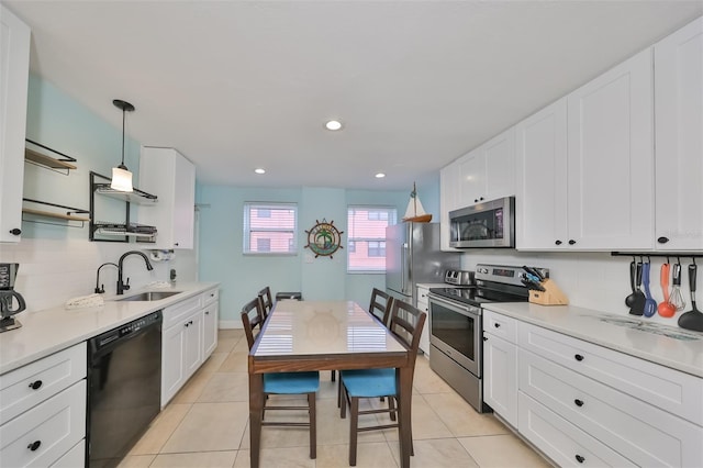 kitchen with appliances with stainless steel finishes, white cabinetry, hanging light fixtures, and sink