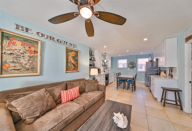 tiled living room with ceiling fan, sink, and a textured ceiling