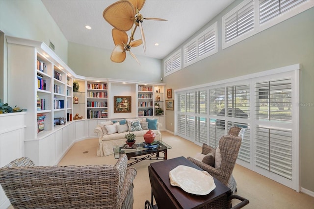 interior space featuring light colored carpet, plenty of natural light, a high ceiling, and ceiling fan