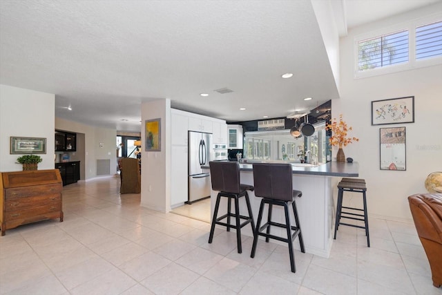 kitchen with sink, white cabinetry, stainless steel fridge, and light tile patterned flooring