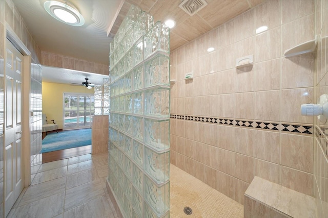 bathroom featuring tile walls, tile patterned floors, a shower, and ceiling fan