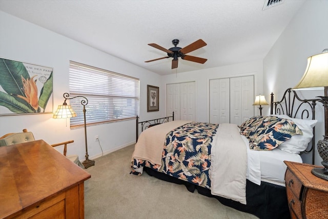 carpeted bedroom featuring ceiling fan and multiple closets