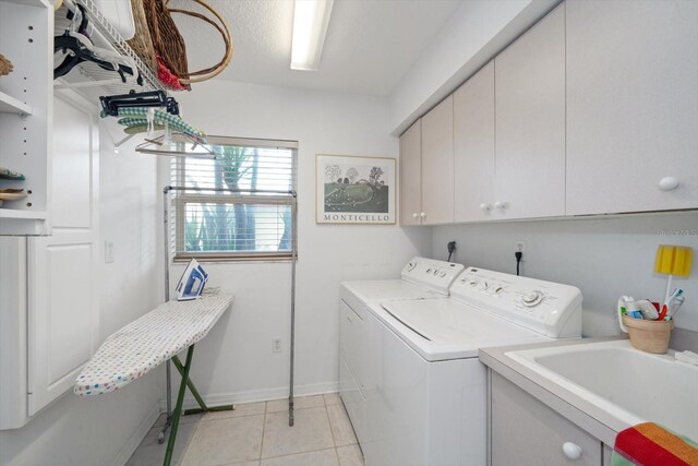 laundry room featuring sink, washer and dryer, cabinets, and light tile patterned floors