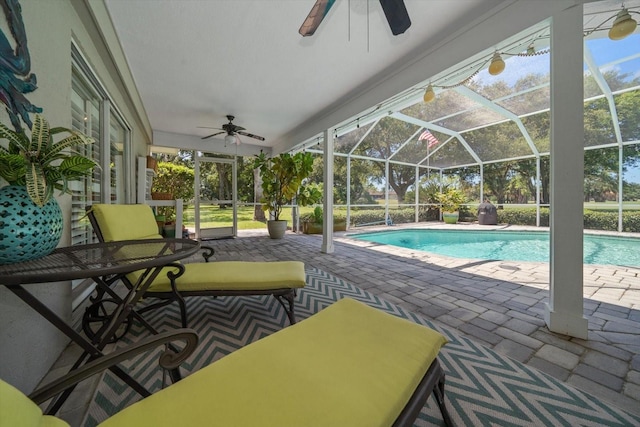 view of pool with ceiling fan, glass enclosure, and a patio