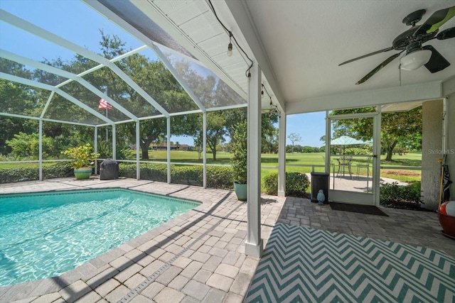 view of swimming pool featuring ceiling fan, a patio, and a lanai