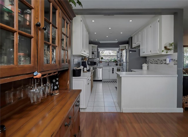 kitchen featuring white cabinets, light wood-type flooring, appliances with stainless steel finishes, and backsplash