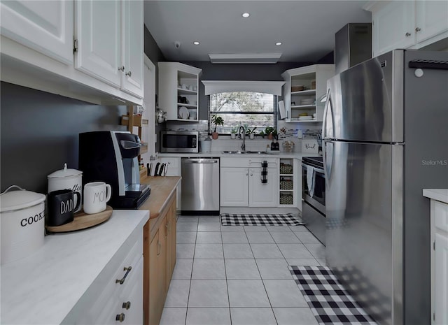 kitchen featuring white cabinetry, stainless steel appliances, sink, and light tile patterned floors