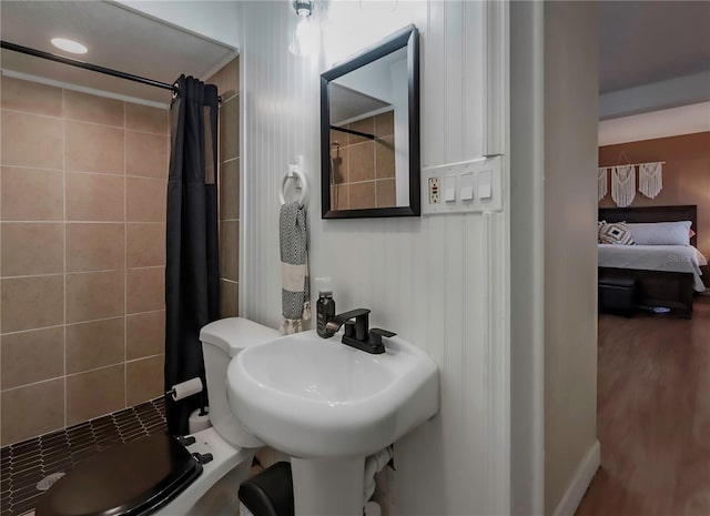 bathroom with hardwood / wood-style floors, sink, toilet, and a shower with curtain