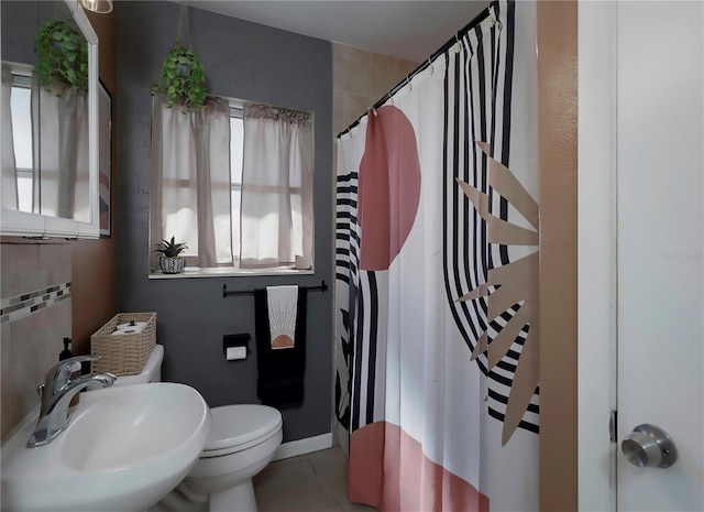 bathroom featuring toilet, tile walls, tile patterned flooring, sink, and walk in shower