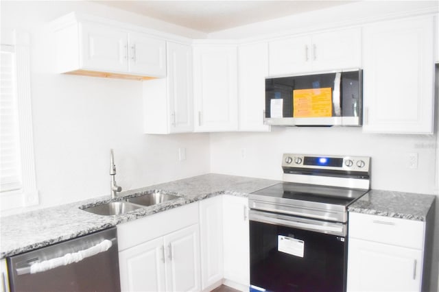 kitchen with appliances with stainless steel finishes, sink, light stone countertops, and white cabinets