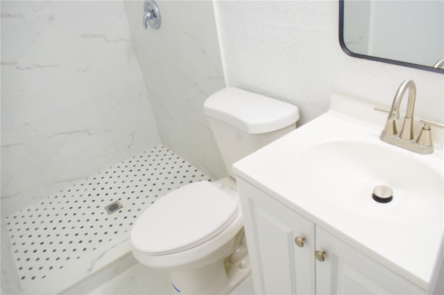 bathroom featuring tile patterned flooring, toilet, a tile shower, and vanity