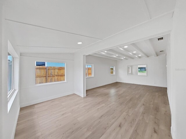 unfurnished living room with beamed ceiling and light hardwood / wood-style flooring