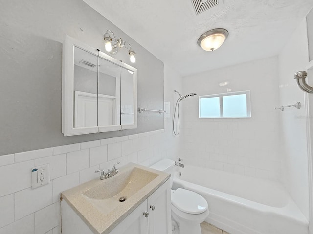 full bathroom featuring decorative backsplash, toilet, vanity, tile walls, and tiled shower / bath combo