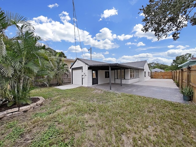 back of property featuring a patio, a garage, and a yard