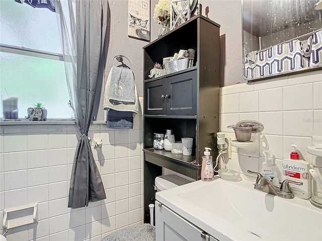 bathroom featuring tile walls, vanity, and toilet