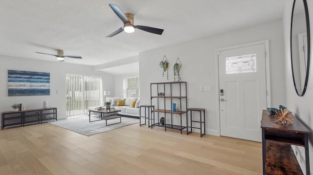 foyer entrance featuring ceiling fan, light hardwood / wood-style flooring, and a textured ceiling