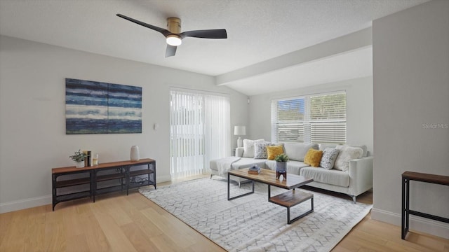 living room with ceiling fan, light hardwood / wood-style floors, a textured ceiling, and lofted ceiling