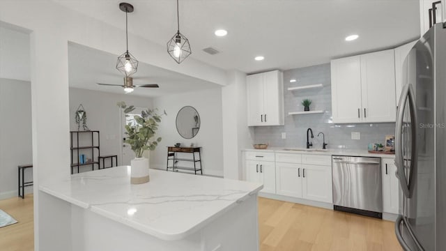 kitchen with ceiling fan, decorative backsplash, white cabinets, appliances with stainless steel finishes, and light hardwood / wood-style floors