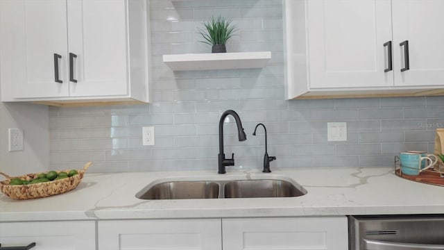 kitchen featuring sink, decorative backsplash, white cabinetry, and light stone countertops