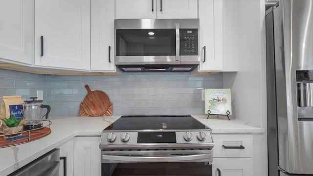 kitchen with decorative backsplash, white cabinetry, light stone counters, and stainless steel appliances