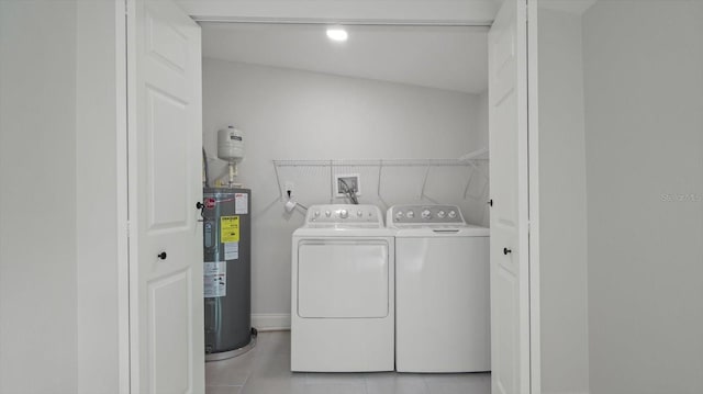 washroom featuring light tile patterned flooring, washing machine and dryer, and electric water heater