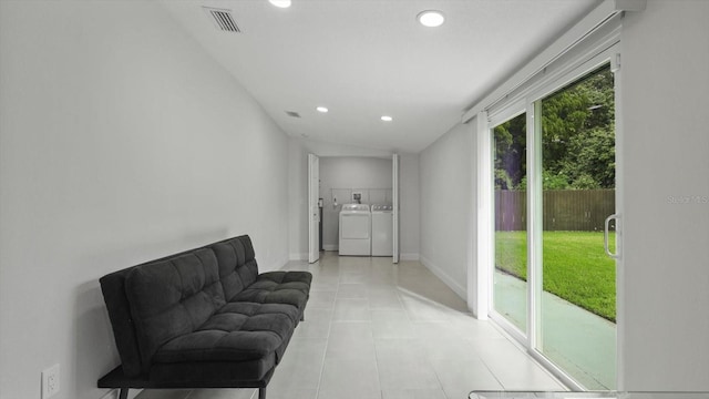 sitting room with washing machine and dryer, vaulted ceiling, a healthy amount of sunlight, and light tile patterned floors