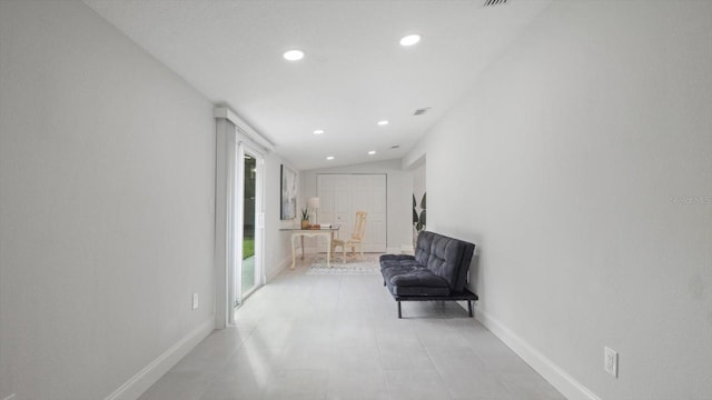 corridor with lofted ceiling and light tile patterned floors