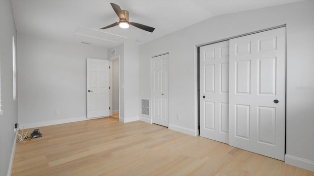 unfurnished bedroom featuring light wood-type flooring, two closets, ceiling fan, and lofted ceiling